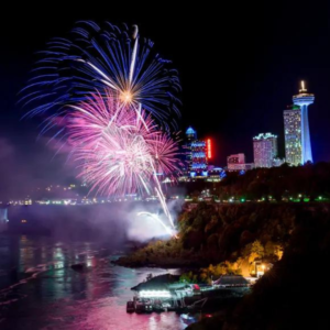 Colorful fireworks lighting up the night sky over Niagara Falls, reflecting on the water below.